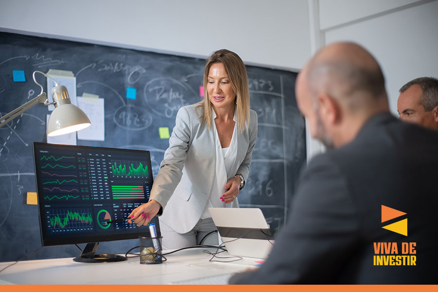empresaria apresentando um grafico de investimentos no computador para outros 2 empresarios