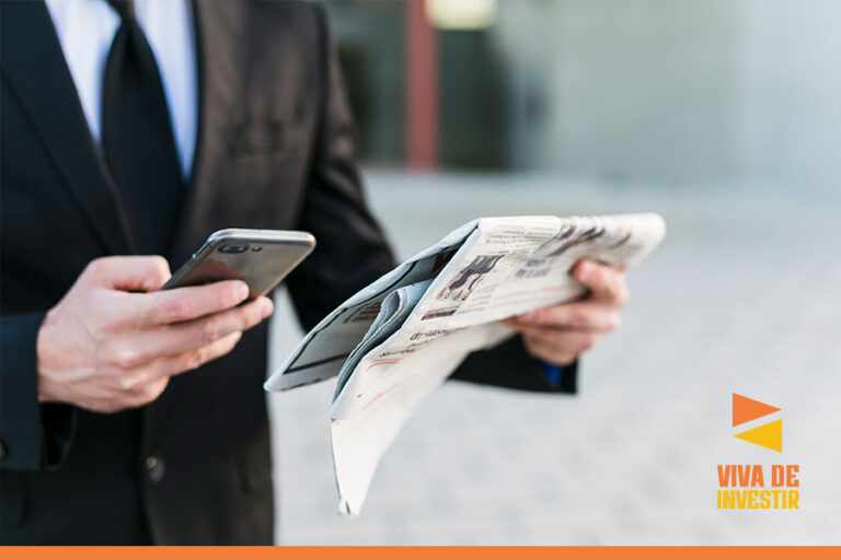 empresario caminhando com o jornal numa mao e celular na outra mao